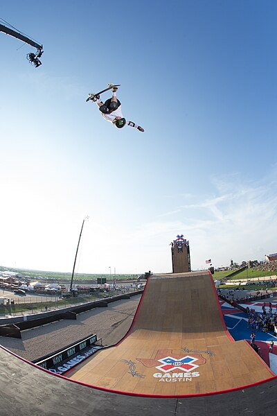 Atleta de skate realizando salto sobre rampa.