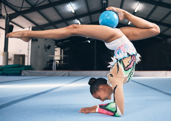 Atleta de ginástica rítmica realiza movimento de cabeça com bola.