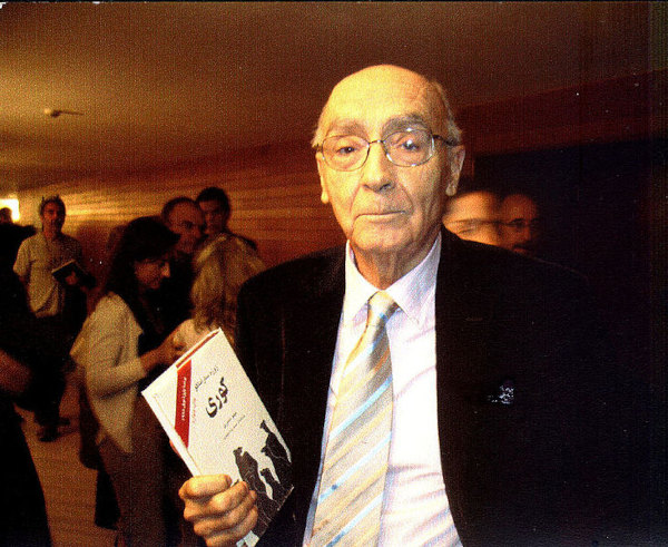 Fotografia do escritor português José Saramago segurando um livro em mãos.