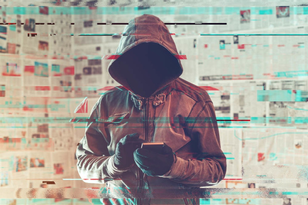 Homem, usando luvas e blusa de frio com capuz, mexendo no celular, uma alusão a um dos recursos associados à misantropia.