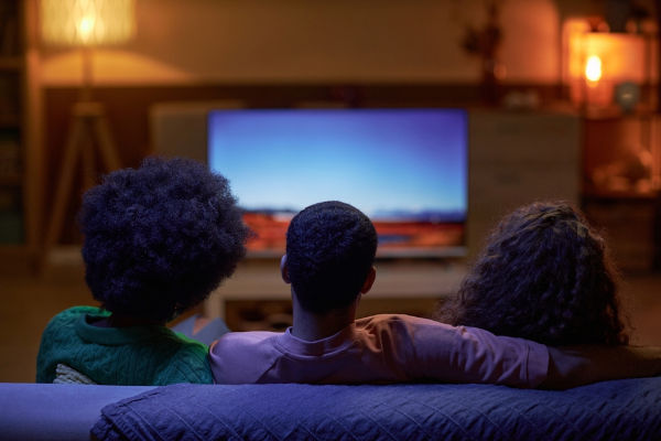 Três telespectadores assistindo a algo na televisão.