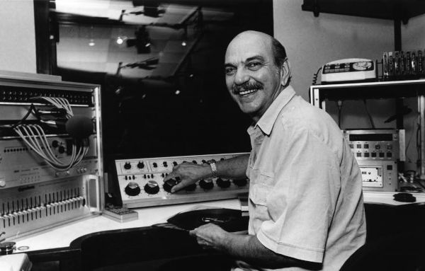 Foto em preto e branco de Lima Duarte ao lado de equipamentos em estúdio de rádio.