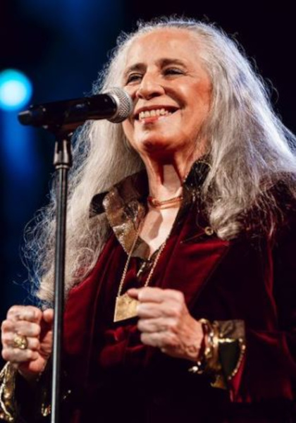 Cantora Maria Bethânia sorrindo em apresentação musical.