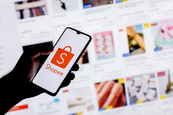 Mão segurando celular com aplicativo de compras online aberto, uma forma de importação.