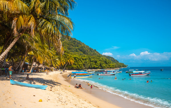 Barcos e banhistas em uma praia de Honduras.