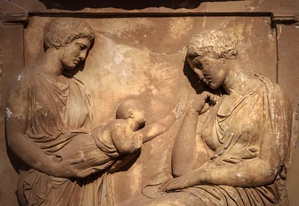 "Escultura grega representando duas mulheres, uma delas segurando um bebê"  Veja mais sobre "Período Helenístico" em: https://brasilescola.uol.com.br/historiag/periodo-helenistico.htm
