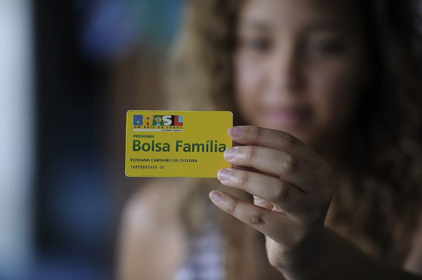 Mulher segura cartão do Bolsa Família.