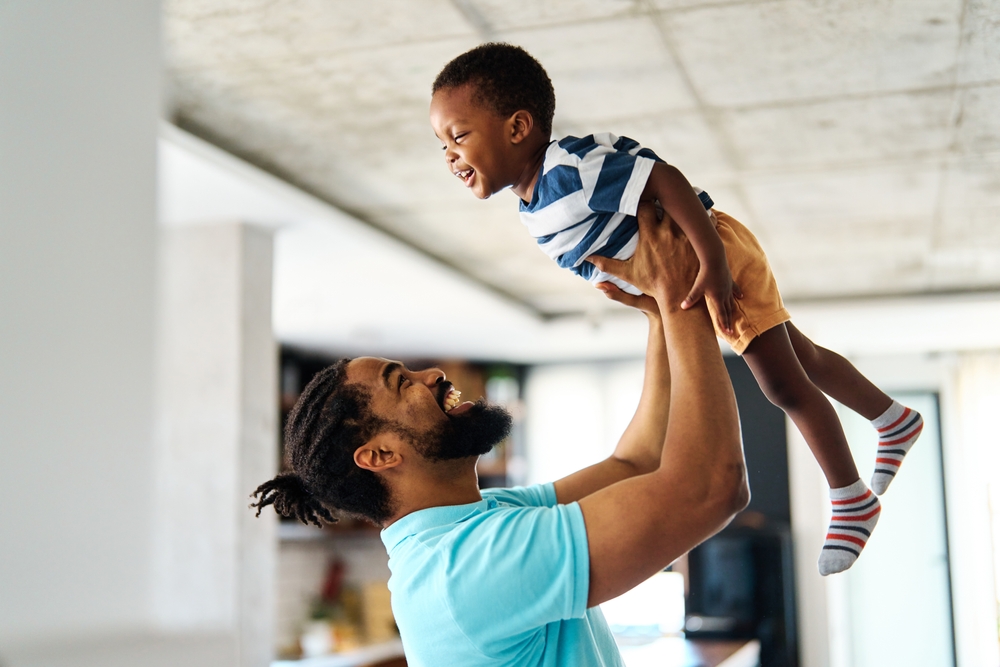 Pai e filhos negros em momento de brincadeira