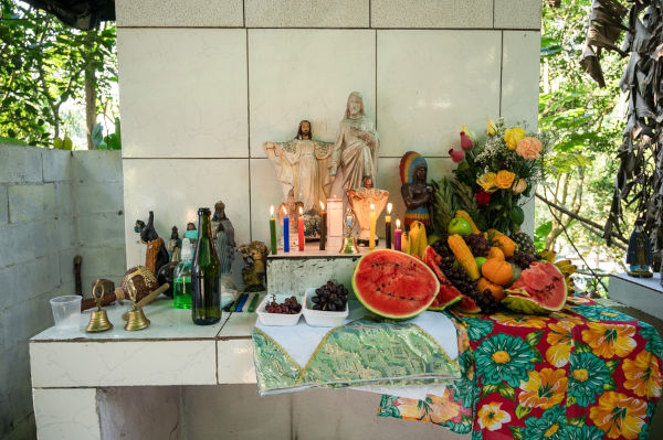 Altar com oferendas a santos e a orixás, em referência ao sincretismo das religiões no Brasil.