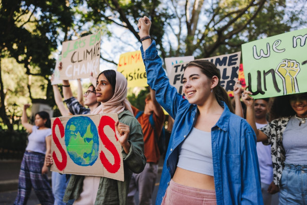 Jovens da geração Z erguendo mãos e faixas em um protesto.