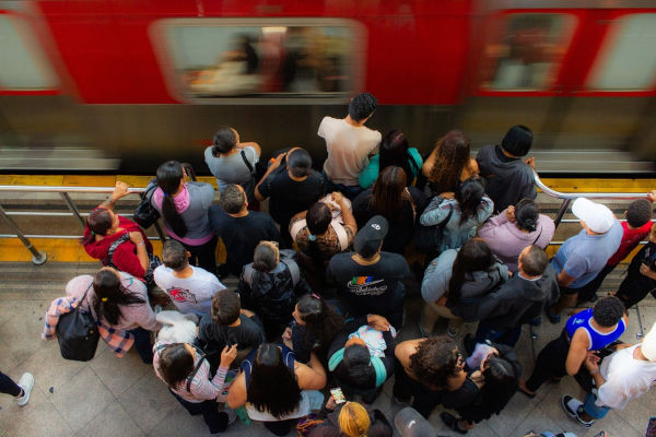 Amontoado de pessoas diante de metrô, em referência à migração pendular.