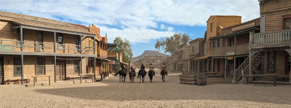 Quatro caubóis cavalgando em réplica de uma cidade do Velho Oeste, na Espanha. 