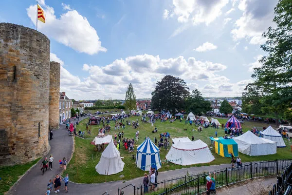 Feira comercial ao redor de um castelo, uma alusão às feiras comerciais comuns na Baixa Idade Média.