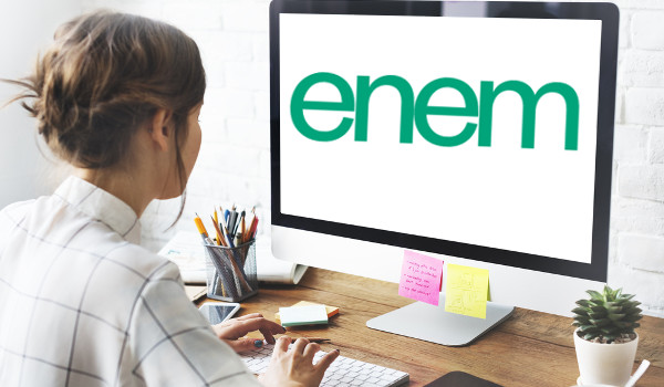 Estudante em computador que mostra na tela a logomarca do Enem