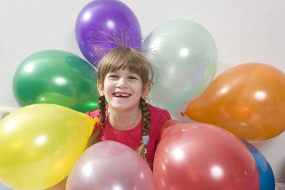Os cabelos da menina estão eletrizados e são atraídos pelos balões – essa é uma evidência da natureza elétrica da matéria