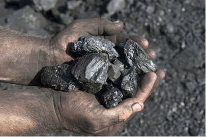 Mãos de mineiro com carvão mineral