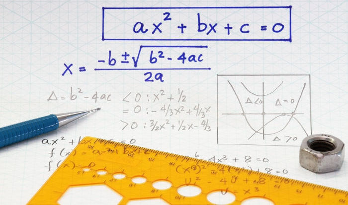 Fórmula de Bhaskara escrita sobre papel ao lado de uma lapiseira e uma régua.