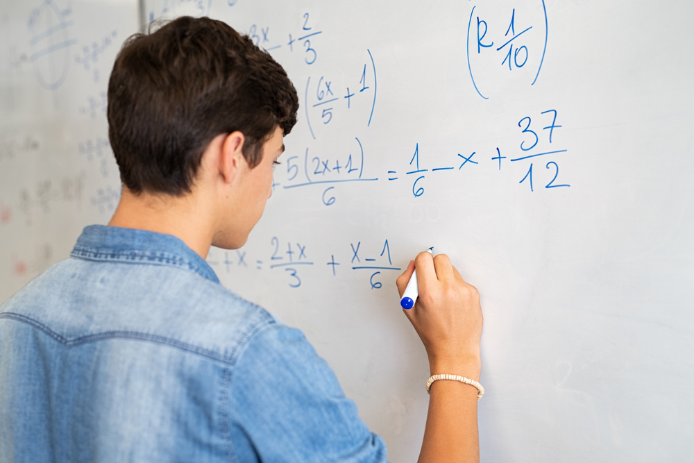 Garoto escreve fórmulas matemáticas de costas