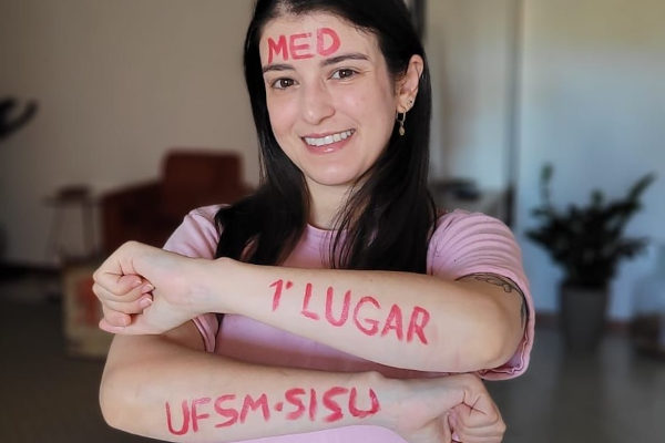 Amanda Pizarro é uma mulher branca e mostra na foto escrito de aprovação em 1º lugar em Medicina
