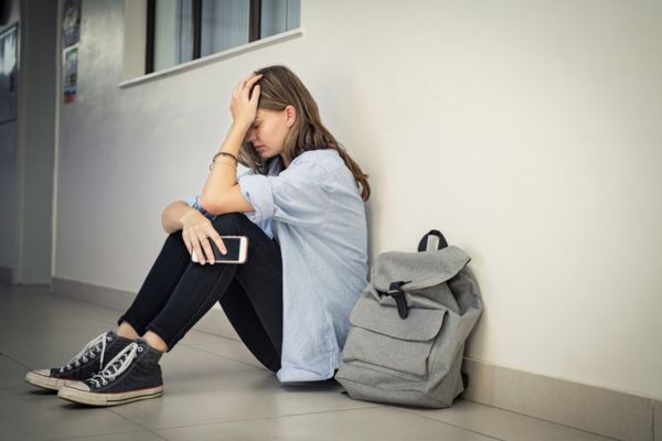 Estudante triste olha para o chão em referência à eliminiação no Enem 2024.