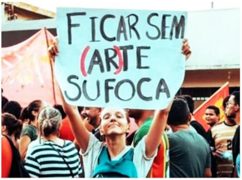 Garota segura cartaz, onde se lê: “Ficar sem (AR)te sufoca”.