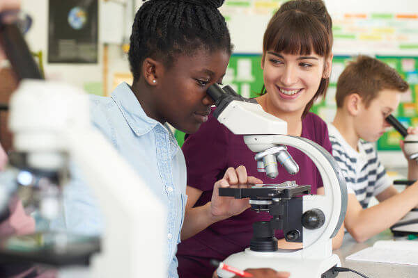 Alunos olhando no microscópio em uma aula de Biologia.