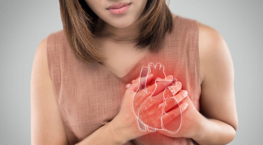 Mulher com a mão no coração em referência ao infarto em mulheres.