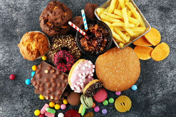 Imagem de alimentos ricos em carboidratos, como chocolate,, bolos e rosquinhas.