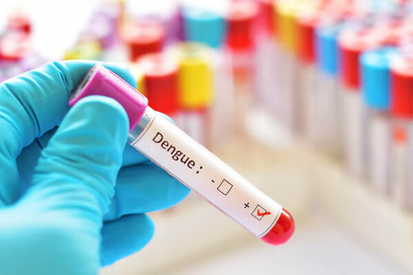 Profissional com um tubo de ensaio com sangue para o diagnóstico da dengue.