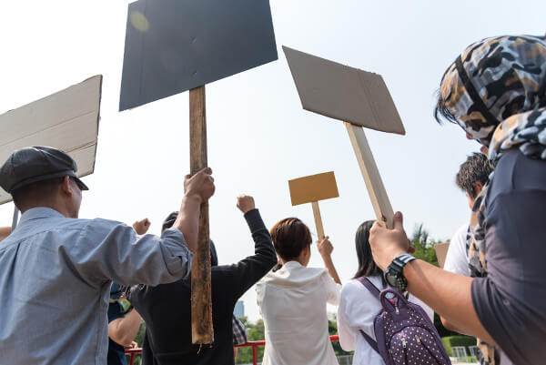 Pessoas de costas segurando placas em protesto, um modo de participação democrática.