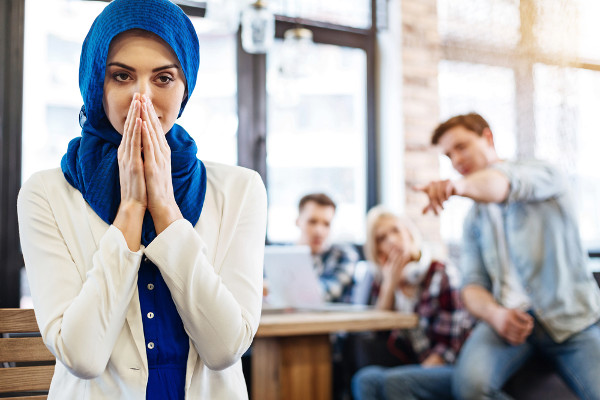 Homem apontando para mulher usando hijab em referência à intolerância religiosa.