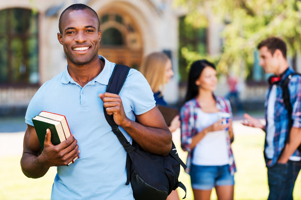 Jovem negro com livros na mão em referência às cotas raciais.