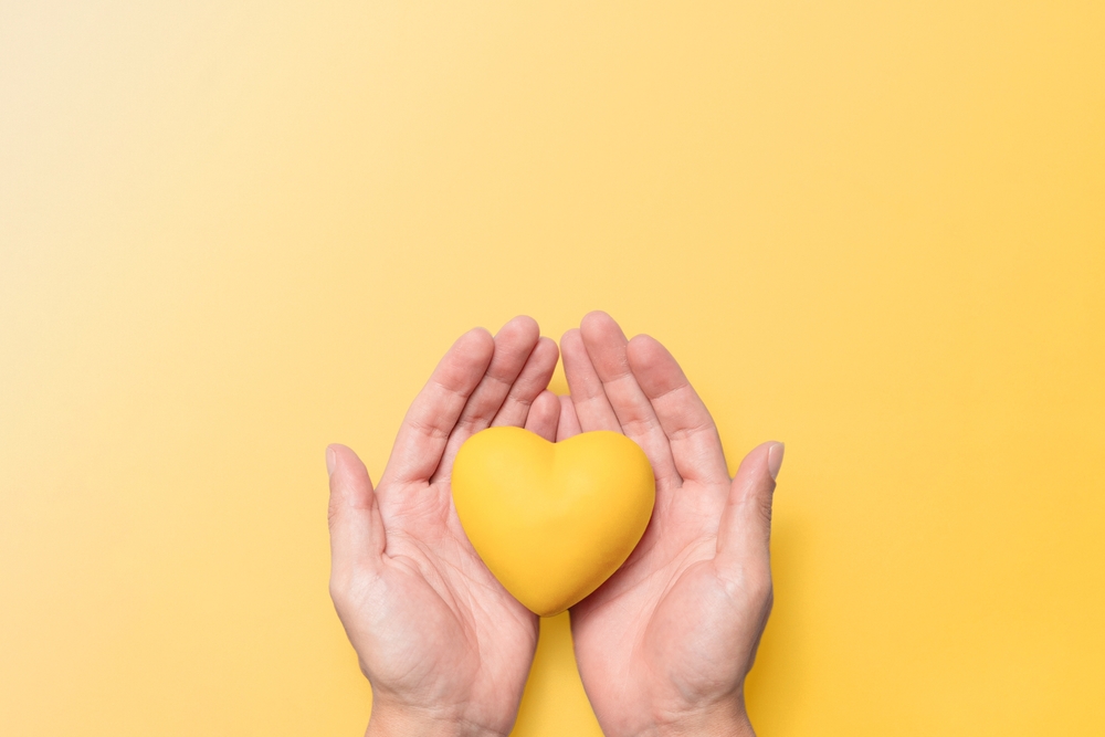 Duas mãos segurando um coração amarelo
