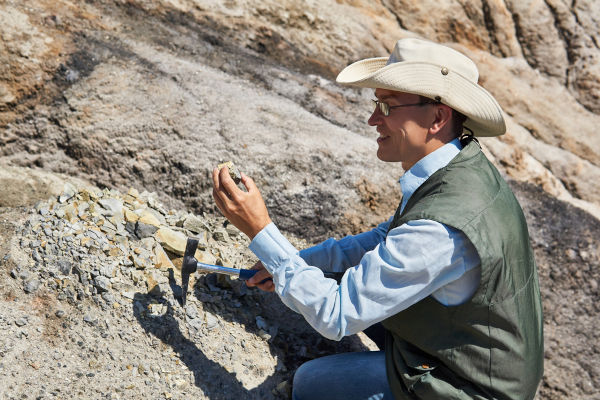geólogo com óculos e chápeu em meio a pedras